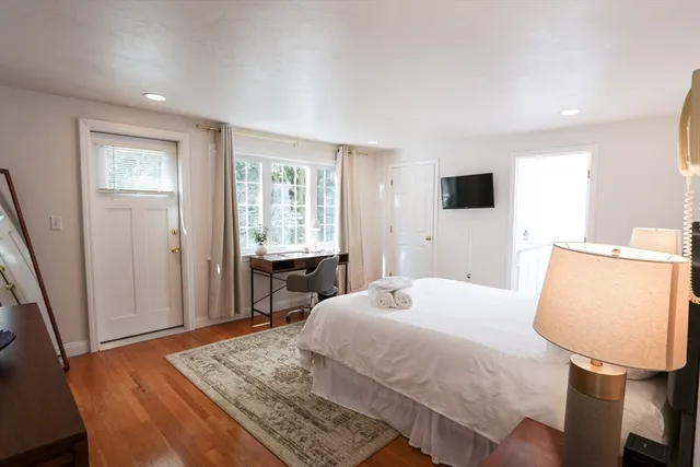 a bedroom with a bed a window and wooden floor
