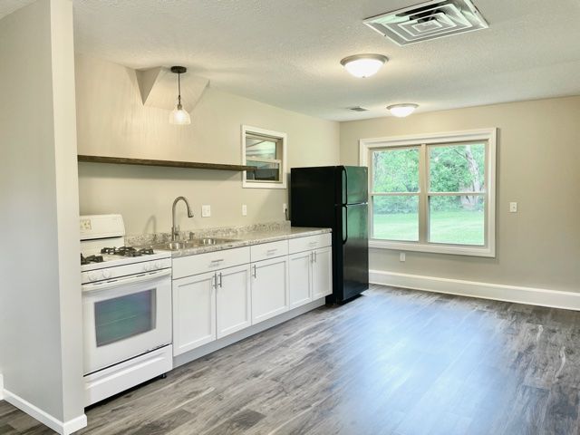 1028 Franklin Grove Road Dixon, IL 61021 - Photo 41 of 48 a kitchen with sink a stove and white cabinets with wooden floor