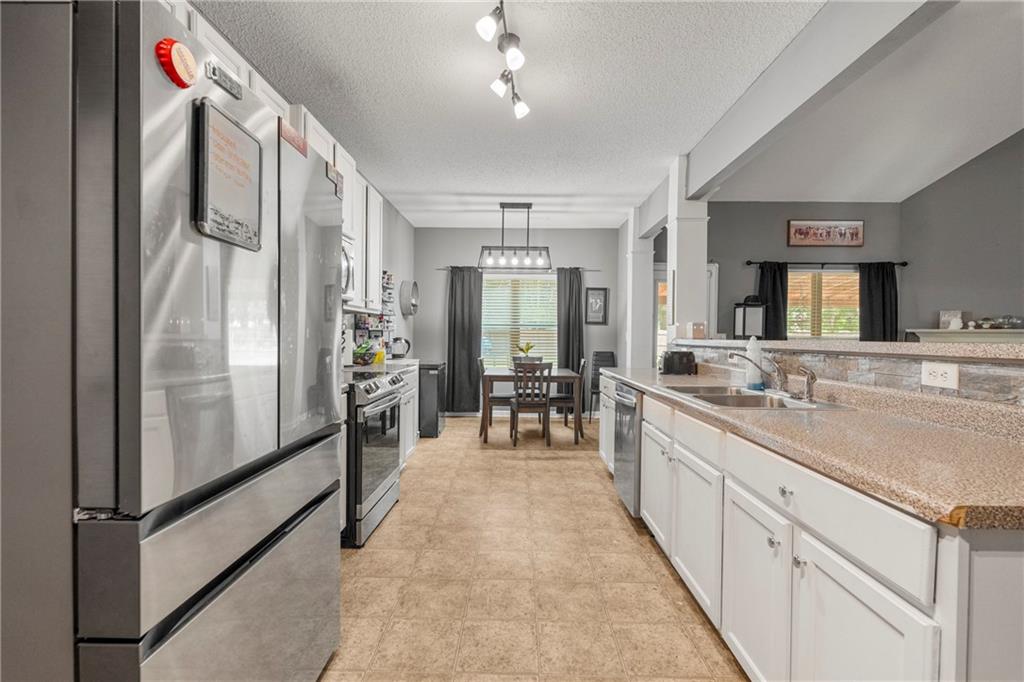 234 Owens Road Fort Mitchell, AL 36856 - Photo 9 of 25 Kitchen featuring stainless steel appliances, a sink, white cabinets, plenty of natural light, and a textured ceiling
