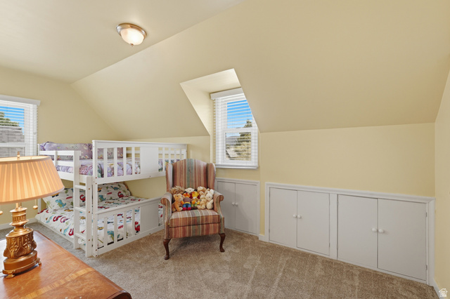 7576 South Jefferson Street Midvale, UT 84047 - Photo 25 of 53 Carpeted room featuring a sloped ceiling, two windows with blinds, and built-in storage cabinets
