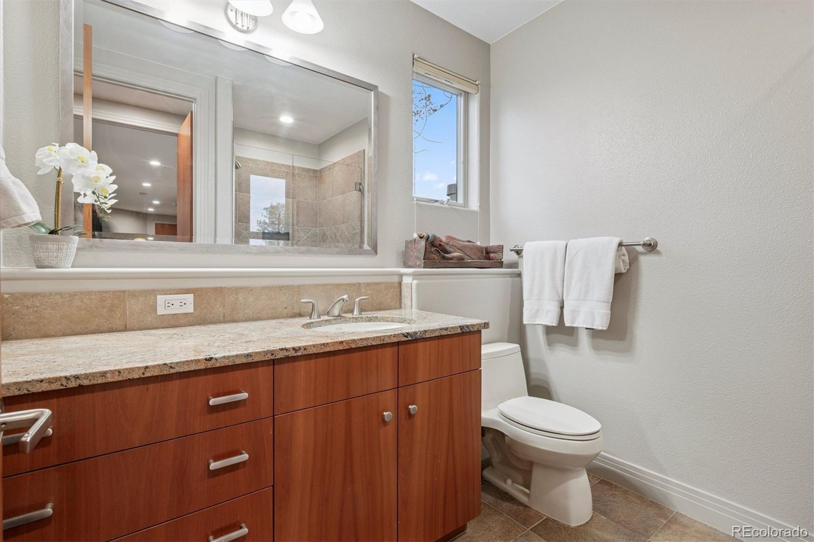 23534 Waynes Way Golden, CO 80401 - Photo 45 of 50 a bathroom with a granite countertop sink a toilet and mirror