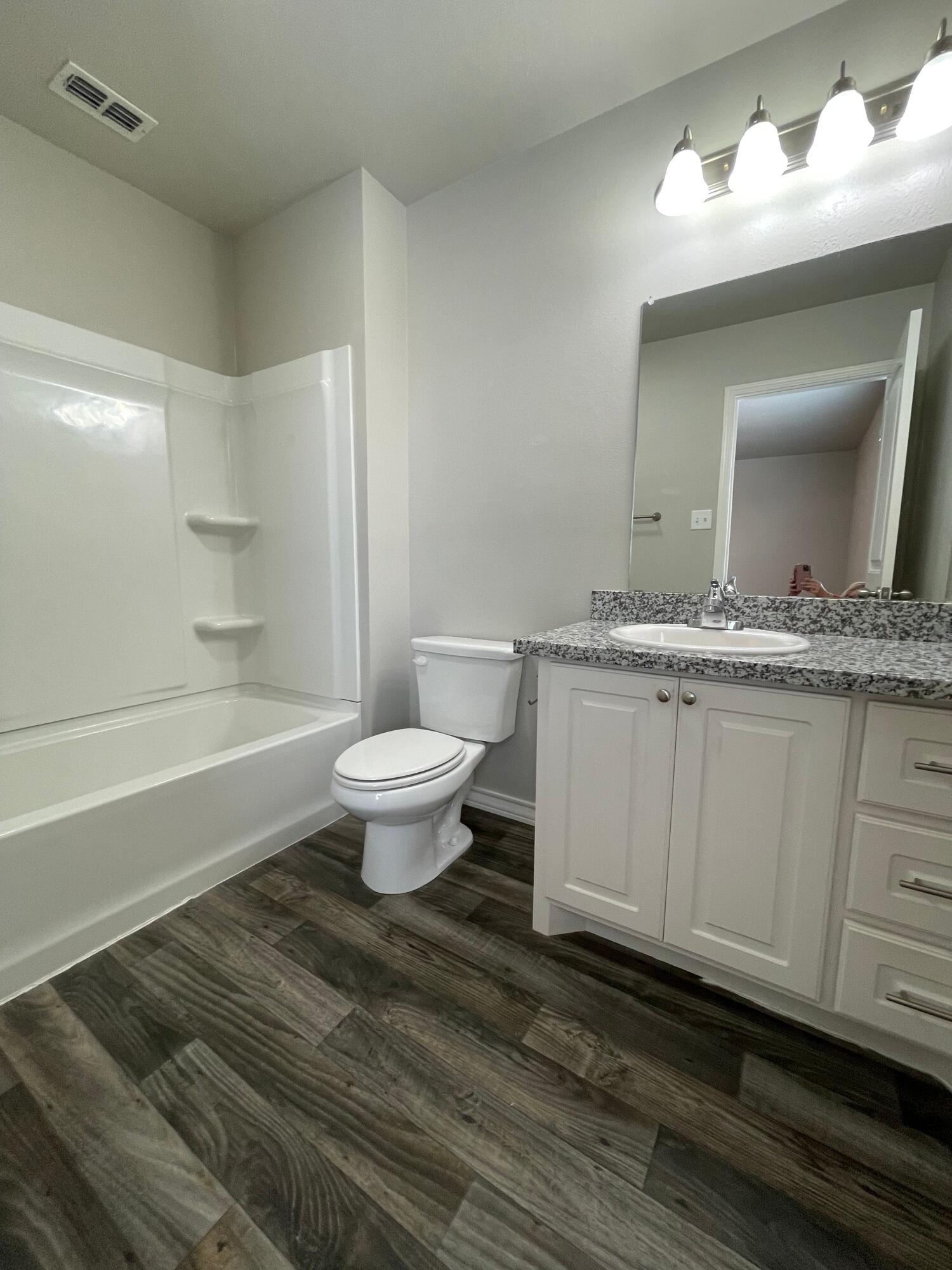 6040 24th Street, Unit 39 Lubbock, TX 79407 - Photo 11 of 13 a bathroom with a granite countertop sink toilet a mirror and bathtub
