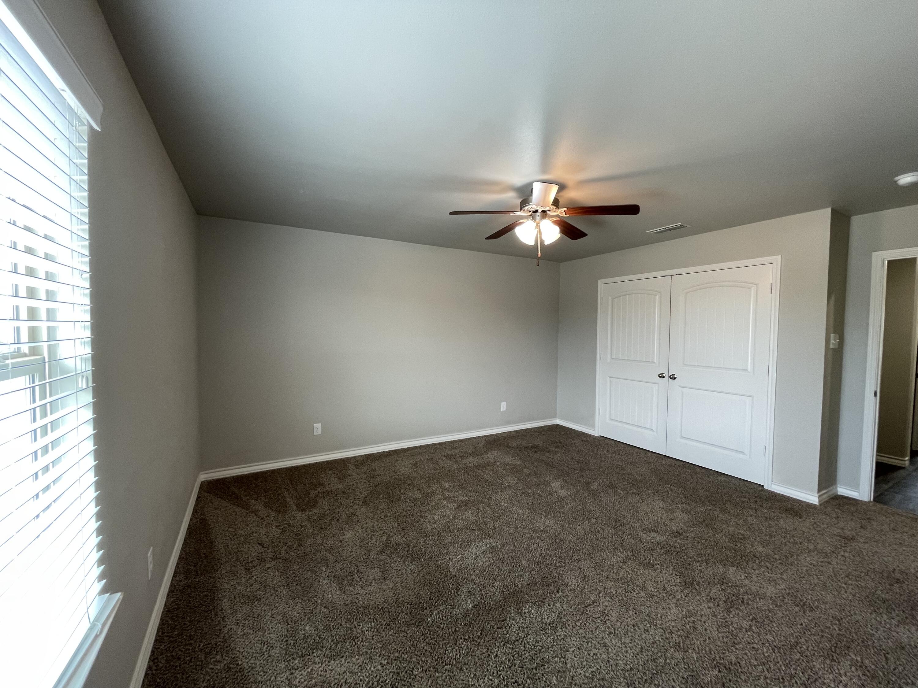 6040 24th Street, Unit 39 Lubbock, TX 79407 - Photo 12 of 13 an empty room with a chandelier fan and windows