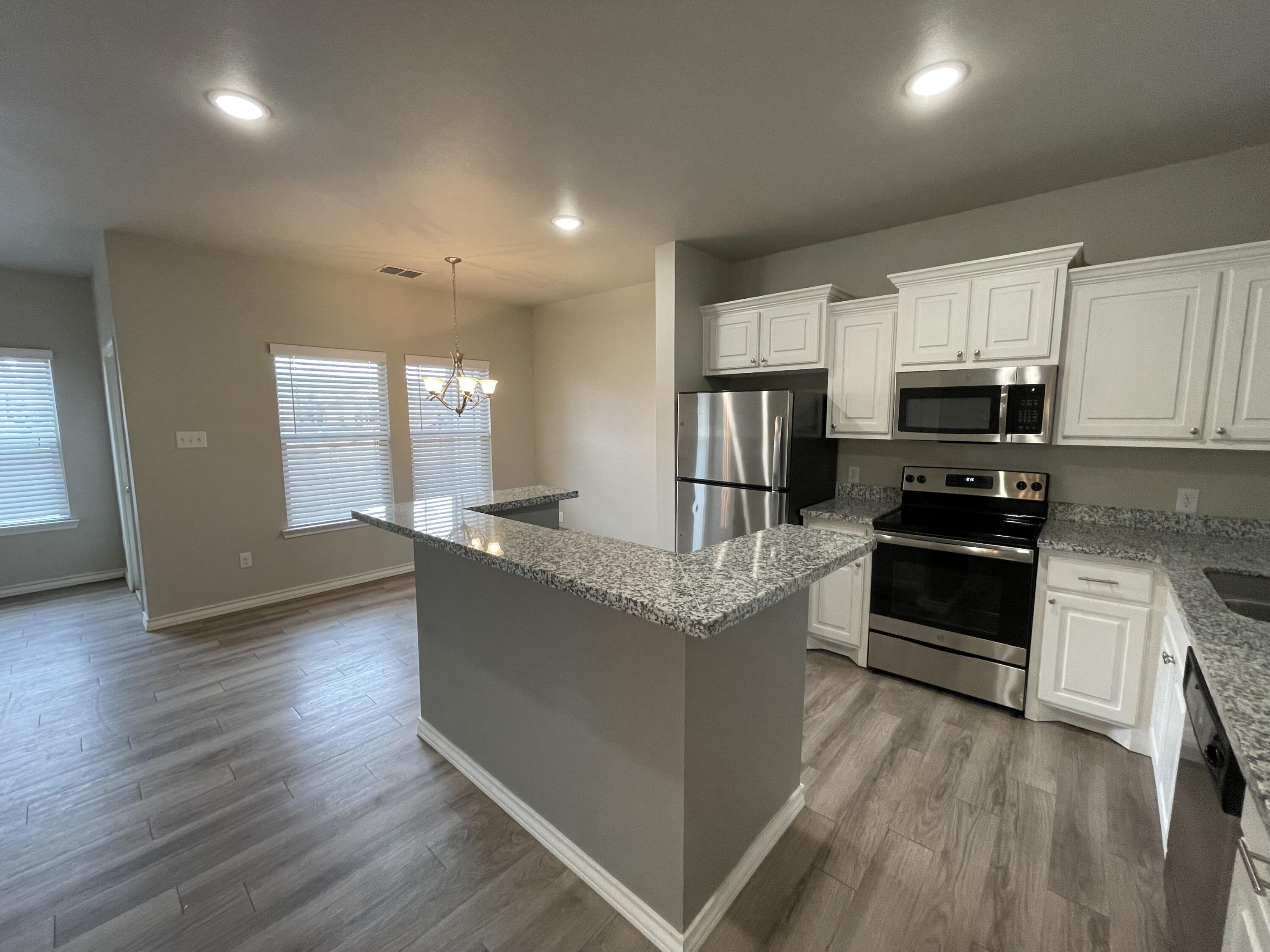 6040 24th Street, Unit 39 Lubbock, TX 79407 - Photo 3 of 13 a kitchen with granite countertop a stove top oven and cabinets