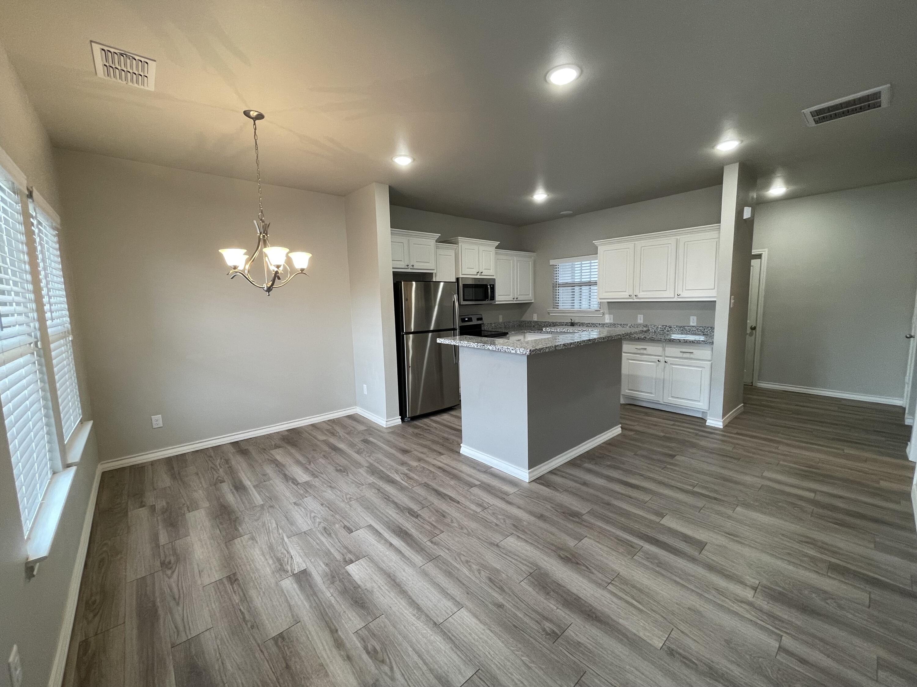 6040 24th Street, Unit 39 Lubbock, TX 79407 - Photo 5 of 13 a view of a kitchen with a sink and dishwasher a refrigerator with wooden floor