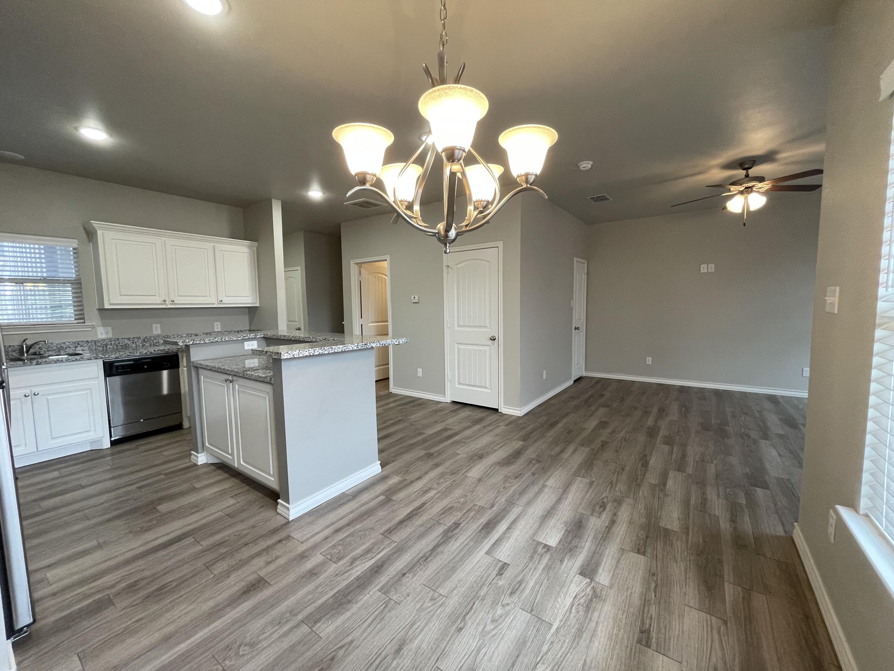 6040 24th Street, Unit 39 Lubbock, TX 79407 - Photo 6 of 13 a kitchen with a wooden floor cabinets and appliances