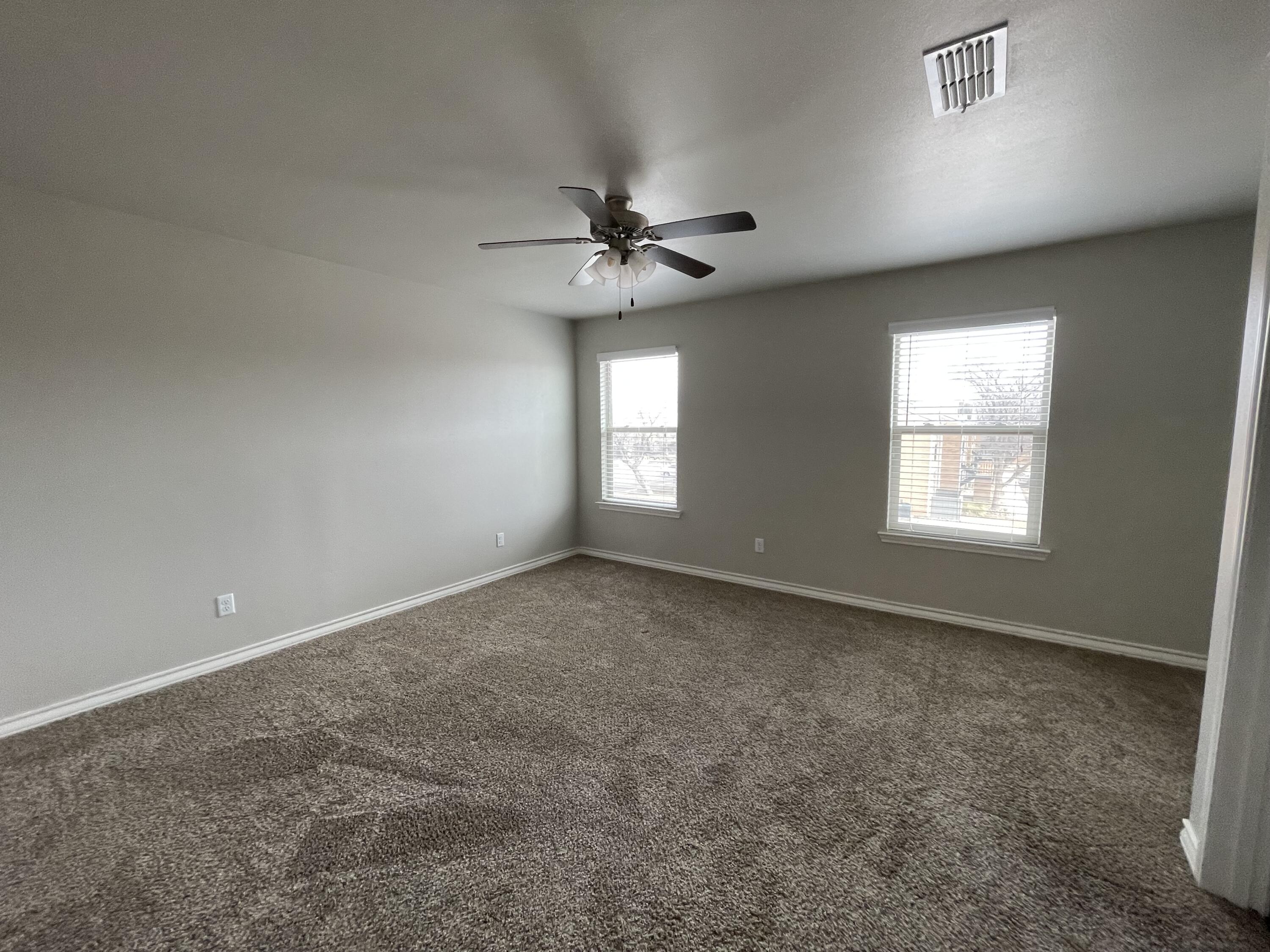 6040 24th Street, Unit 39 Lubbock, TX 79407 - Photo 9 of 13 an empty room with windows and ceiling fan