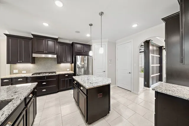 a large kitchen with stainless steel appliances kitchen island granite countertop a sink stove and refrigerator