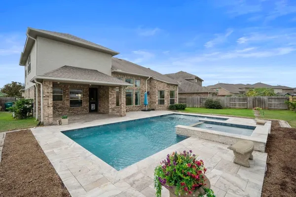 a view of swimming pool with outdoor seating and house in the background