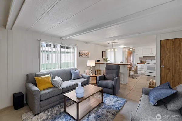 a kitchen with stainless steel appliances kitchen island granite countertop a dining table chairs and a refrigerator