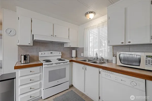 a kitchen with granite countertop a sink a stove a refrigerator and a stove