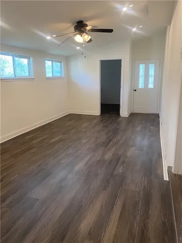 a view of an empty room with wooden floor and a ceiling fan