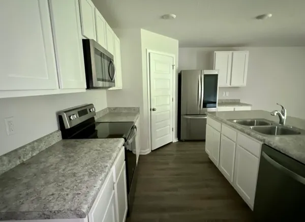 a kitchen with granite countertop a sink a counter top space stainless steel appliances and cabinets