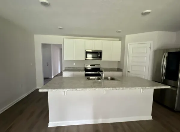 a large white kitchen with kitchen island a sink a stove and a refrigerator