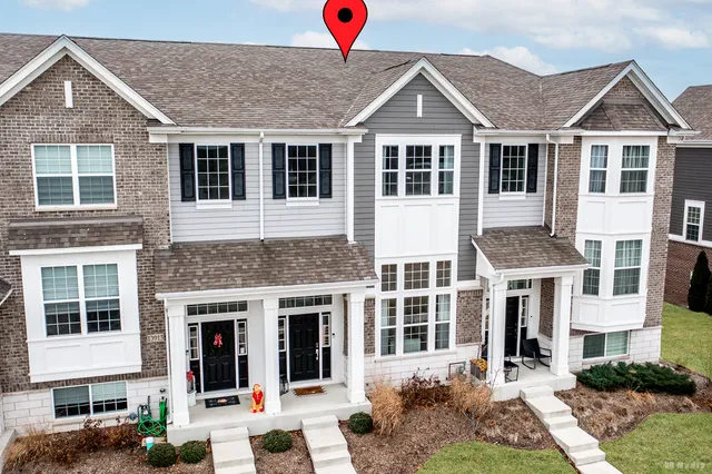 a view of a white house with large windows next to a yard