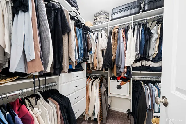a view of walk in closet with clothes and shoes
