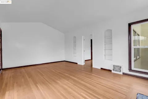 a view of an empty room with wooden floor and a window