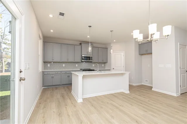 a kitchen with stainless steel appliances granite countertop white cabinets and a stove top oven