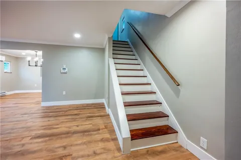 a view of an empty room and kitchen space with wooden floor