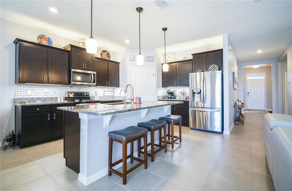 6250 Southwest 89th Ln Road Ocala, FL 34476 - Photo 37 of 71 a kitchen with stainless steel appliances kitchen island granite countertop a refrigerator a stove a oven a sink a dining table and chairs