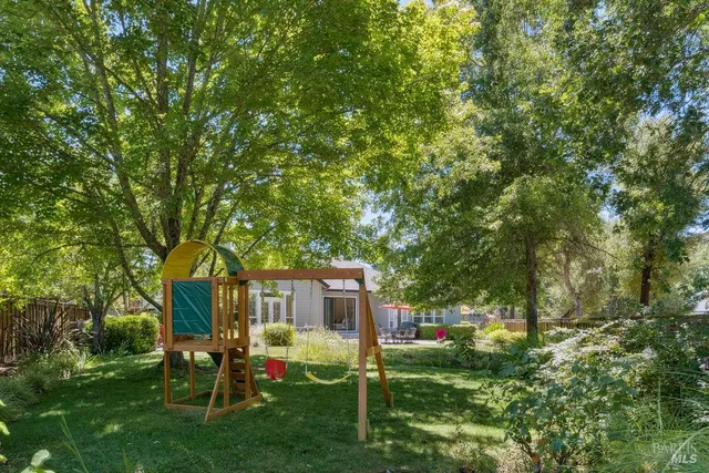 a view of backyard with table and chairs and large trees