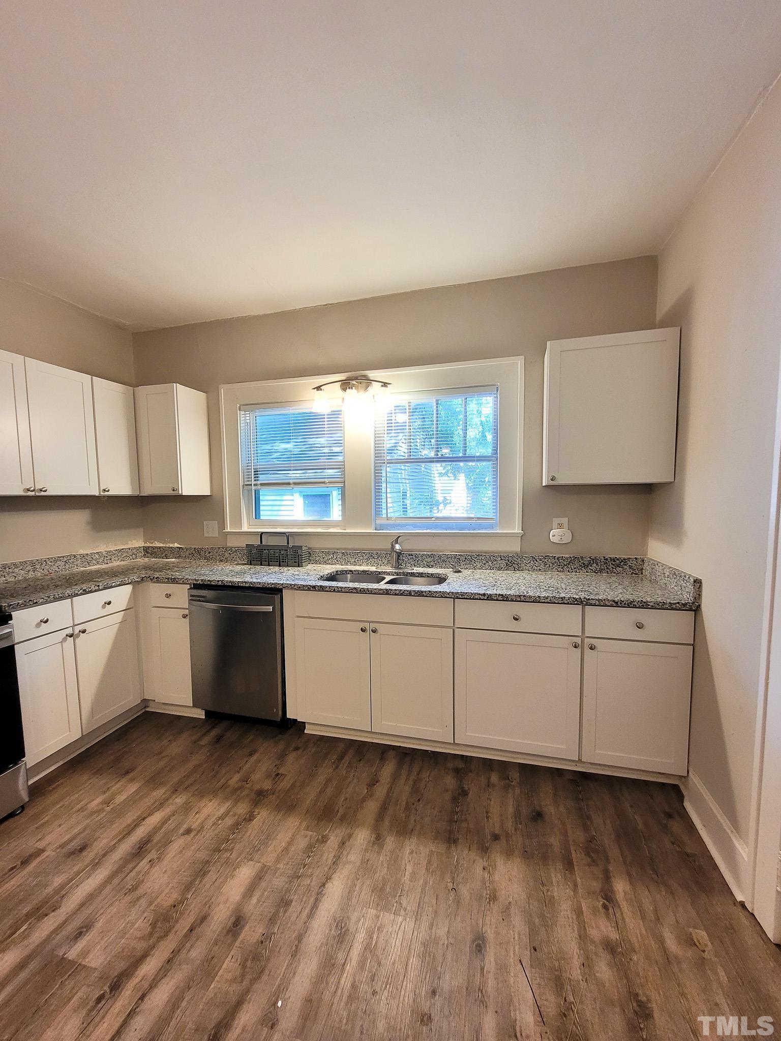 802 Park Avenue, Unit B Durham, NC 27703 - Photo 19 of 23 a large white kitchen with granite countertop a stove top oven a sink and dishwasher with wooden floor