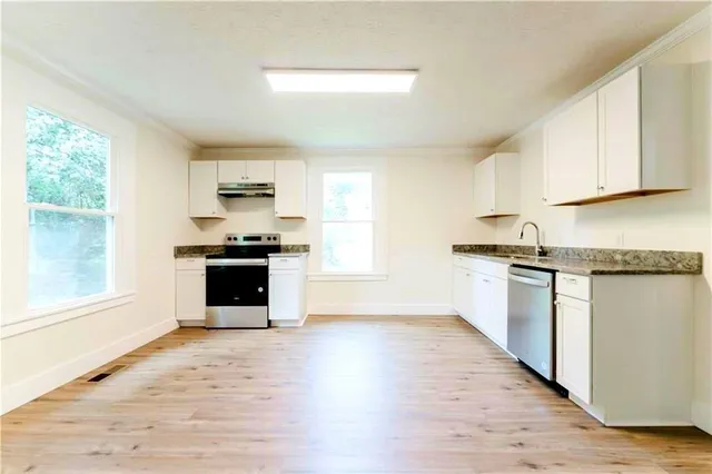 a kitchen with granite countertop a refrigerator and a stove top oven