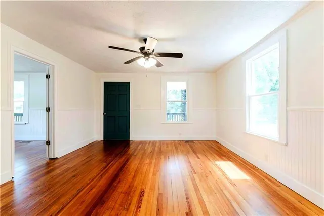 a view of empty room with wooden floor and fan