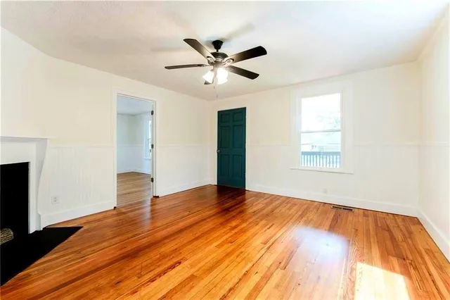 a view of an empty room with wooden floor and a window