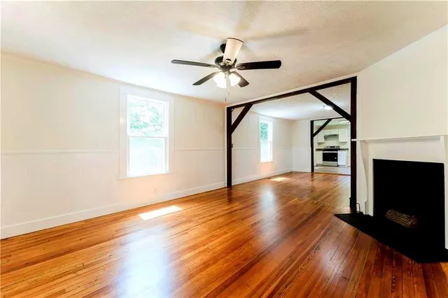 a view of a livingroom with wooden floor a ceiling fan and windows