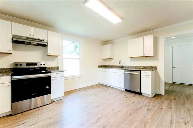 a kitchen with granite countertop wooden floors and white stainless steel appliances