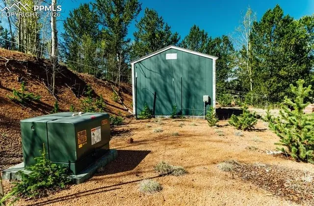 a backyard of a house with large trees and wooden fence
