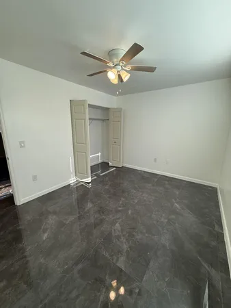 an empty room with closet and a ceiling fan