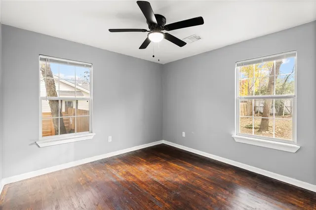 an empty room with wooden floor and a ceiling fan