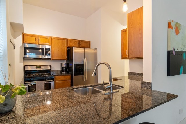 2441 West Harrison Street, Unit 1 Chicago, IL 60612 - Photo 3 of 10 a kitchen with stainless steel appliances granite countertop a sink a stove and a refrigerator with wooden floor
