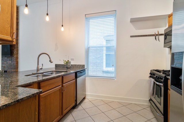 2441 West Harrison Street, Unit 1 Chicago, IL 60612 - Photo 4 of 10 a kitchen with granite countertop a sink a stove and a window