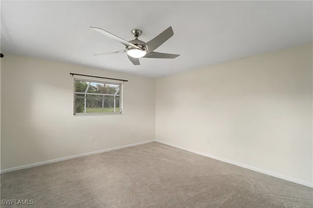 an empty room with a window and ceiling fan