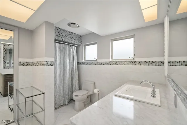 a bath room with a sink a toilet and a mirror