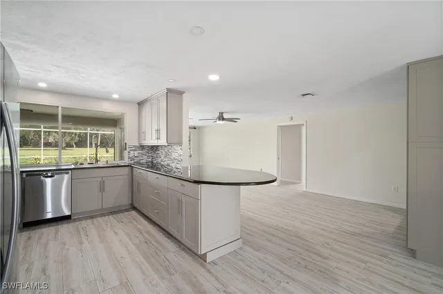 a large kitchen with a sink and wooden floor