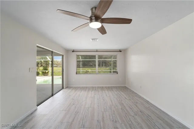 a view of an empty room with wooden floor and a window