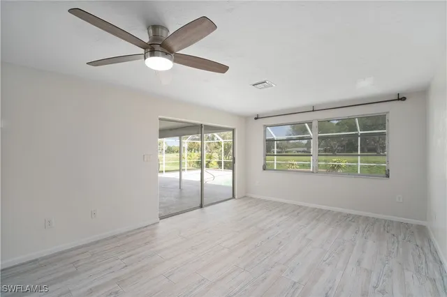 an empty room with wooden floor and windows