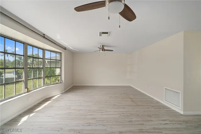a view of an empty room with wooden floor and windows