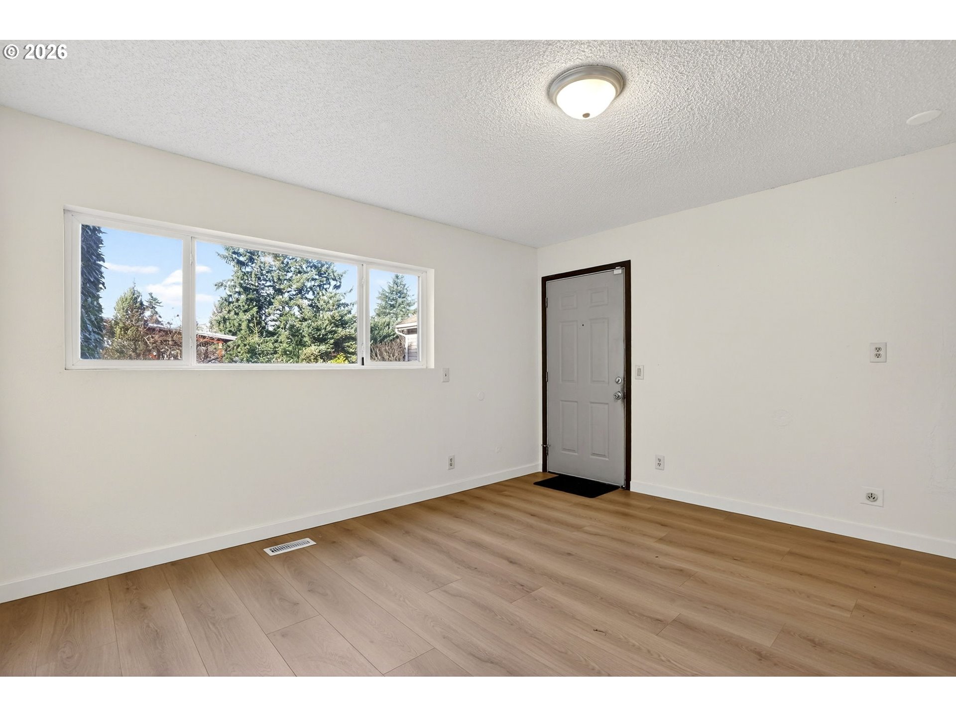 5249 Northeast 45th Place Portland, OR 97218 - Photo 18 of 48 a view of an empty room with wooden floor and a window