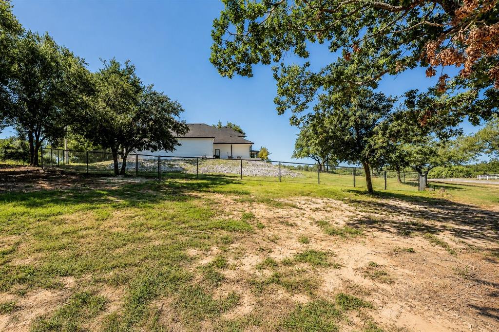 117 Rock Salt Drive Springtown, TX 76082 - Photo 35 of 38 Expansive outdoor space featuring a partial chain-link fence, mature trees, and a distant property structure