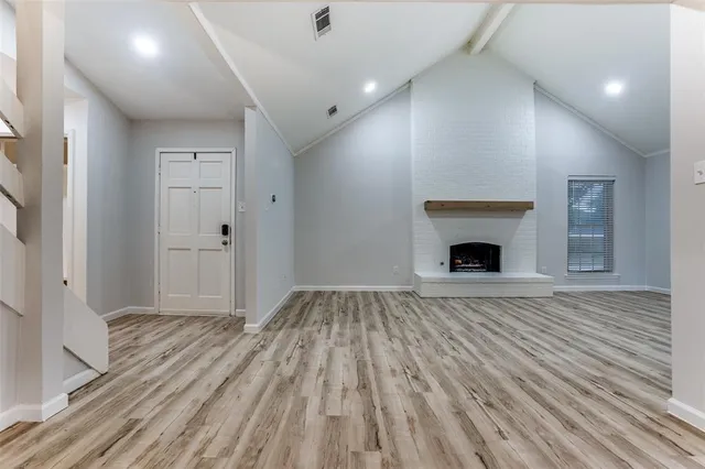 a view of empty room with wooden floor and fireplace