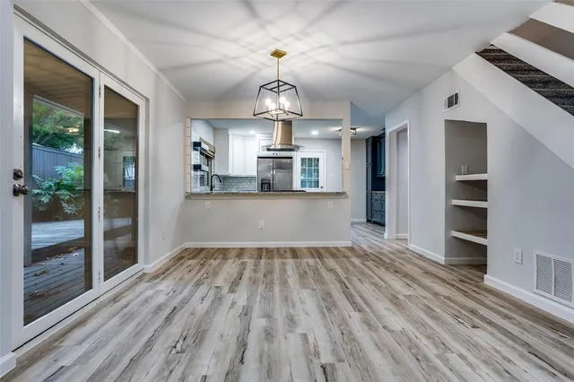 a view of large room with wooden floor kitchen view and windows