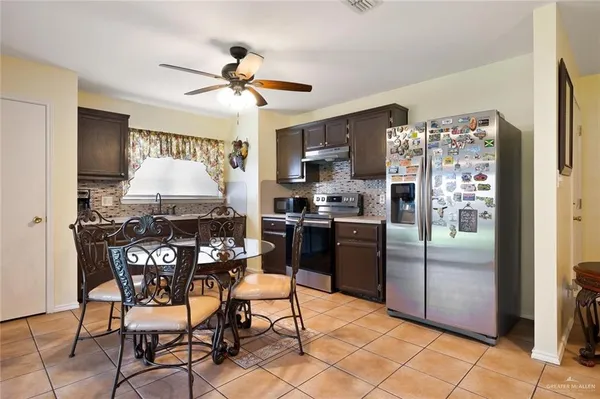 a kitchen with stainless steel appliances a refrigerator a stove a sink and a dining table with chairs
