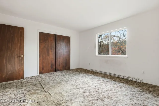 a view of an empty room with window and closet