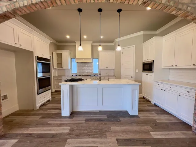 a large kitchen with granite countertop a stove a sink dishwasher a refrigerator and a oven with wooden floor