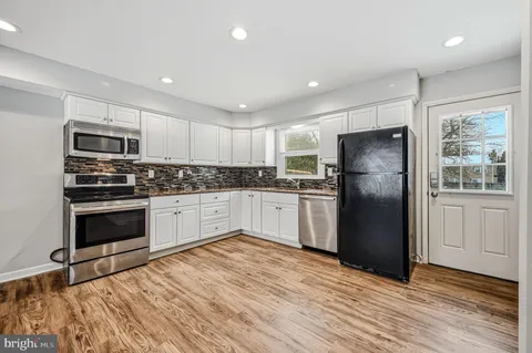 a kitchen with granite countertop a refrigerator stove and microwave